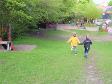To børn løber ned af en græsbakke